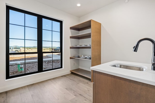 interior space with light hardwood / wood-style floors, light stone counters, and sink