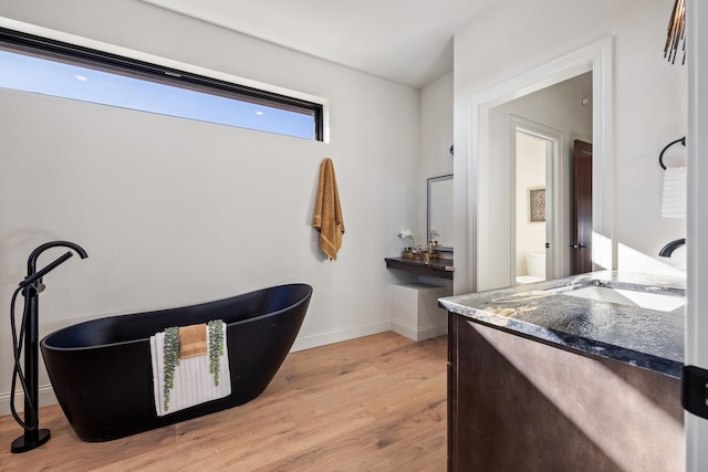 bathroom with hardwood / wood-style flooring, a bathing tub, toilet, and sink