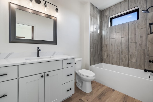 full bathroom with hardwood / wood-style floors, vanity, tiled shower / bath combo, and toilet