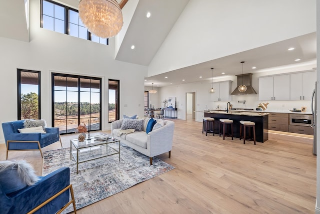 living room with light hardwood / wood-style floors, sink, a high ceiling, and a chandelier