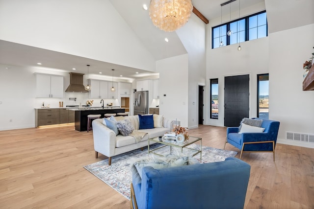 living room featuring light hardwood / wood-style flooring, a towering ceiling, and a notable chandelier