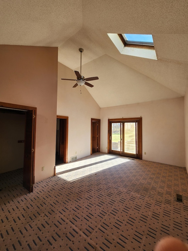 interior space featuring a skylight, ceiling fan, high vaulted ceiling, and a textured ceiling