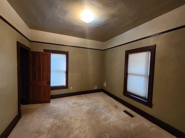 unfurnished room with a textured ceiling and light carpet