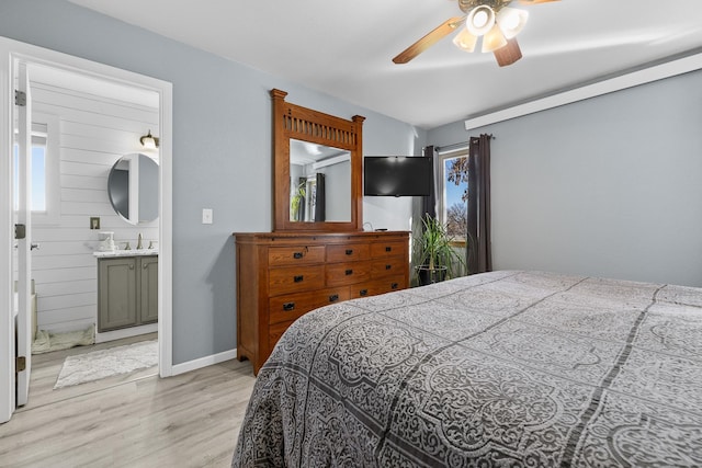 bedroom with ceiling fan, multiple windows, light hardwood / wood-style flooring, and ensuite bath