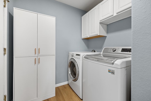 laundry room featuring separate washer and dryer, light hardwood / wood-style flooring, and cabinets