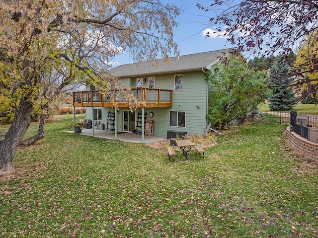 rear view of house featuring a wooden deck, a patio area, and a lawn