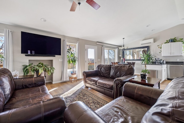 living room with a wall mounted AC, ceiling fan with notable chandelier, lofted ceiling, and light wood-type flooring