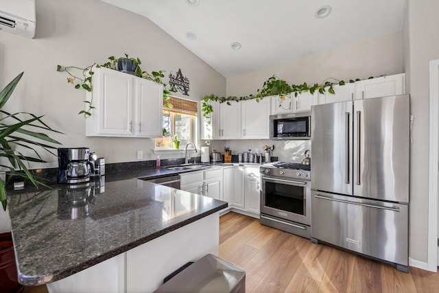 kitchen featuring sink, premium appliances, a wall unit AC, lofted ceiling, and white cabinets