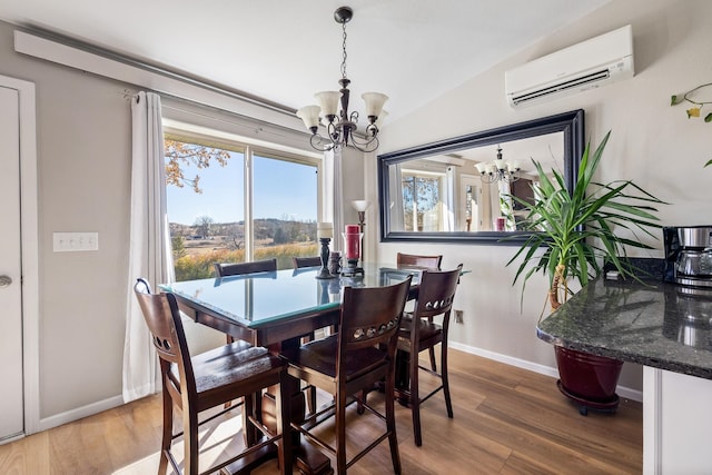 dining room featuring a chandelier, hardwood / wood-style floors, a wall mounted AC, and lofted ceiling