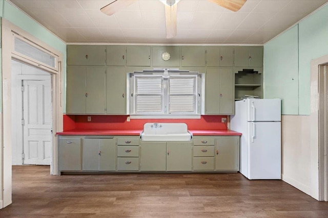 kitchen featuring green cabinetry, white refrigerator, sink, and dark wood-type flooring