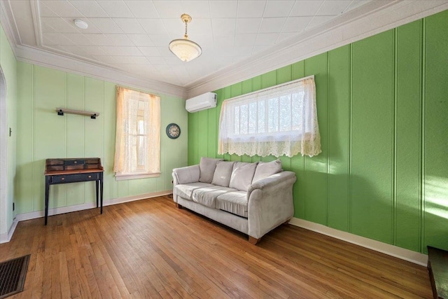 living room featuring hardwood / wood-style flooring, ornamental molding, and a wall unit AC