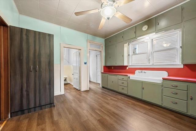 kitchen featuring ceiling fan, sink, wood-type flooring, and green cabinetry