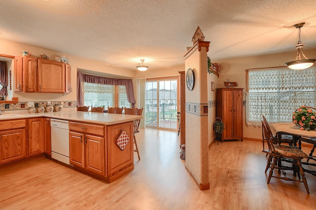 kitchen with dishwasher, light wood-type flooring, a textured ceiling, and decorative light fixtures