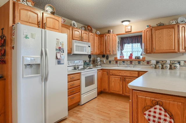 kitchen featuring a textured ceiling, white appliances, light hardwood / wood-style floors, and sink