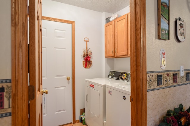 clothes washing area featuring cabinets, a textured ceiling, and washer and dryer