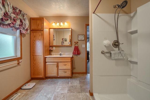 bathroom with vanity, a textured ceiling, and walk in shower