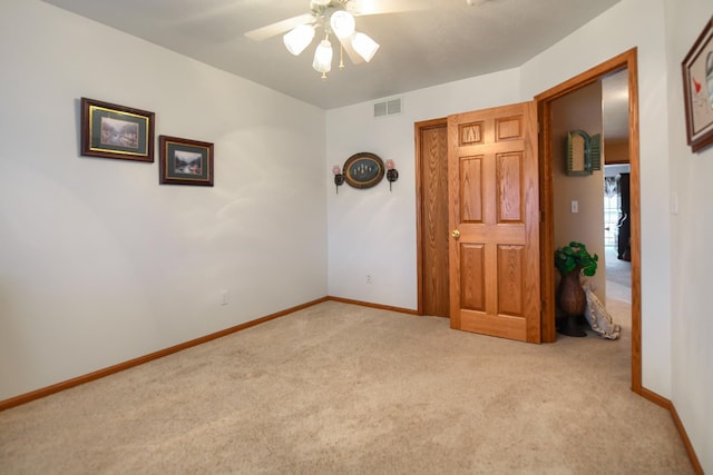 spare room featuring light colored carpet and ceiling fan