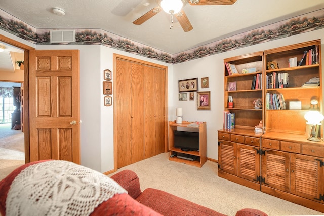 living area featuring carpet flooring, a textured ceiling, and ceiling fan