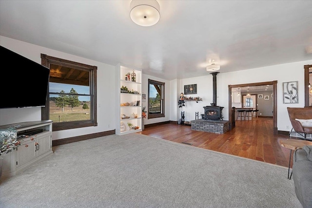 unfurnished living room with a wood stove, a healthy amount of sunlight, and wood-type flooring