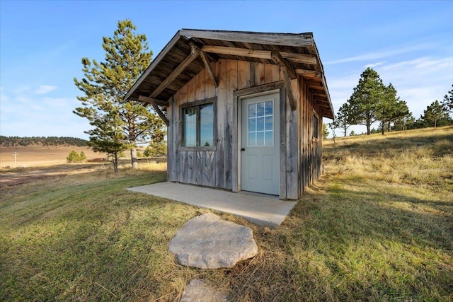 view of outbuilding featuring a rural view and a lawn