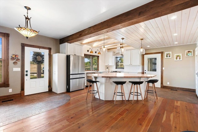 kitchen featuring white cabinets, decorative light fixtures, hardwood / wood-style floors, and appliances with stainless steel finishes