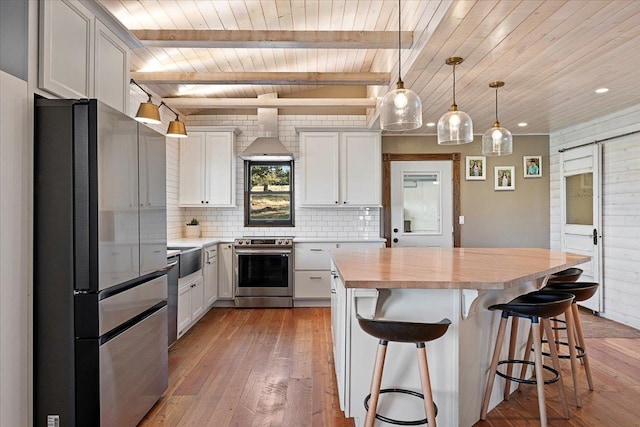 kitchen with white cabinetry, stainless steel appliances, a kitchen breakfast bar, light hardwood / wood-style floors, and decorative light fixtures