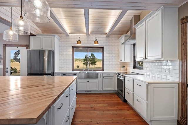 kitchen featuring butcher block countertops, hanging light fixtures, white cabinets, and stainless steel appliances