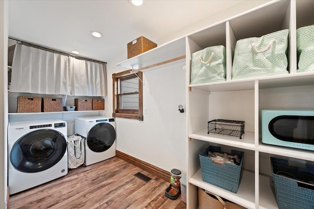 laundry room with hardwood / wood-style floors and washer and dryer