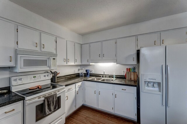 kitchen featuring a textured ceiling, white appliances, dark wood-type flooring, sink, and white cabinets