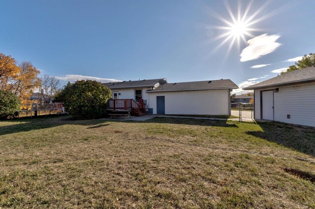 rear view of house featuring a lawn and a wooden deck