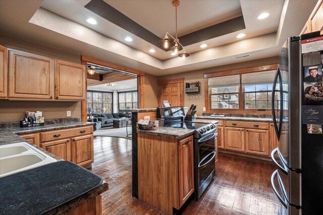 kitchen with stainless steel fridge, a raised ceiling, black range with electric stovetop, and dark wood-type flooring