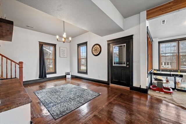 foyer with a notable chandelier, dark hardwood / wood-style floors, a textured ceiling, and a baseboard heating unit