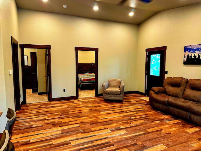 living room featuring a high ceiling, light hardwood / wood-style flooring, and ceiling fan