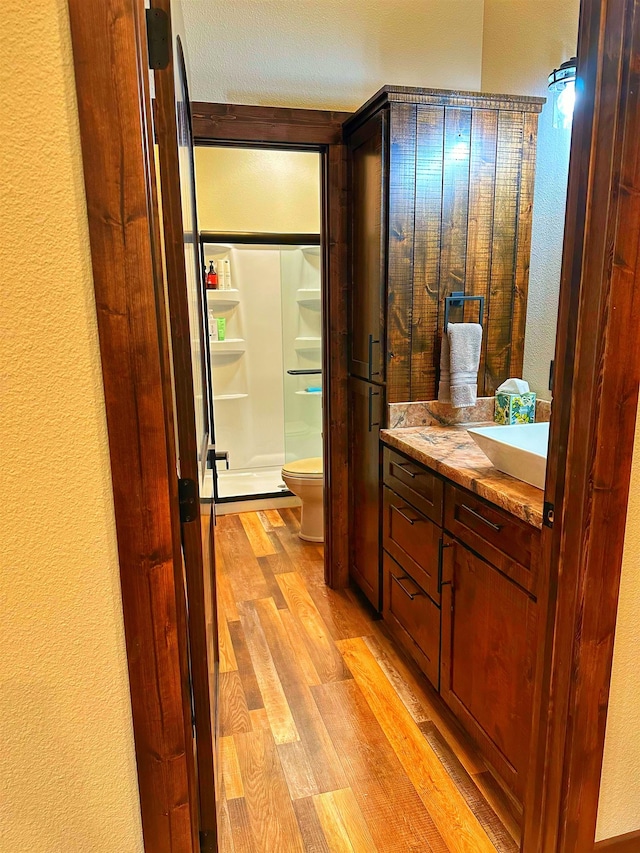 bathroom featuring toilet, hardwood / wood-style floors, vanity, and walk in shower