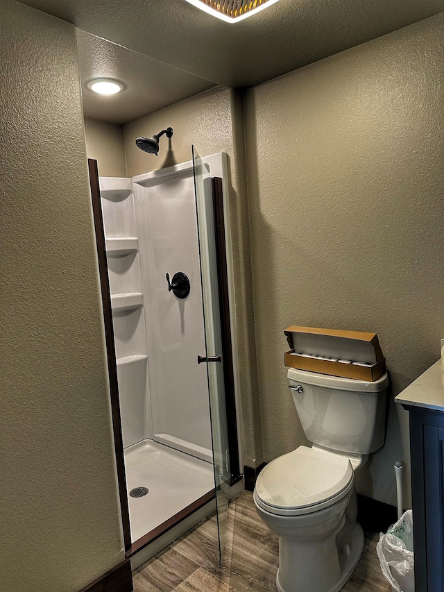 bathroom with toilet, wood-type flooring, a textured ceiling, and walk in shower