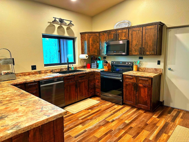 kitchen with sink, stainless steel appliances, and light hardwood / wood-style floors