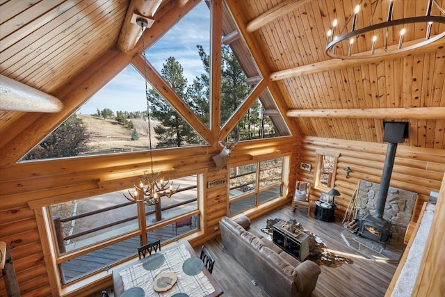 living room featuring a wood stove, high vaulted ceiling, a notable chandelier, beam ceiling, and wood ceiling