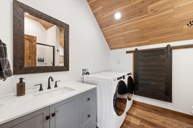 clothes washing area featuring wood ceiling, sink, a barn door, washing machine and clothes dryer, and hardwood / wood-style floors