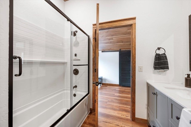 bathroom featuring shower / bath combination with glass door, hardwood / wood-style floors, and vanity