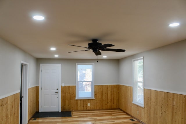 spare room with wooden walls, ceiling fan, and wood-type flooring