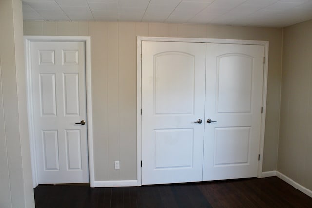 unfurnished bedroom with dark wood-type flooring and a closet