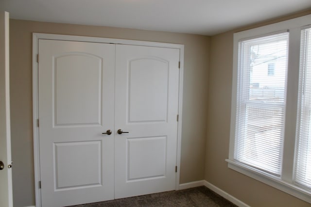 unfurnished bedroom featuring dark colored carpet and a closet