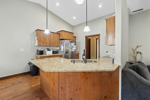 kitchen featuring kitchen peninsula, stainless steel fridge with ice dispenser, sink, and pendant lighting