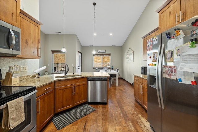 kitchen featuring sink, dark wood-type flooring, lofted ceiling, decorative light fixtures, and appliances with stainless steel finishes