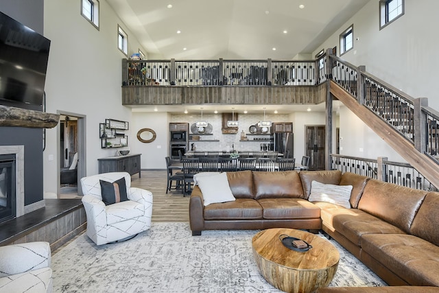 living room featuring hardwood / wood-style flooring, a tile fireplace, and high vaulted ceiling