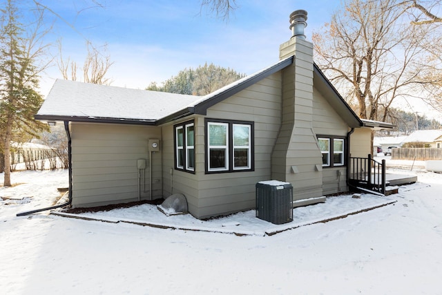 snow covered back of property with central AC