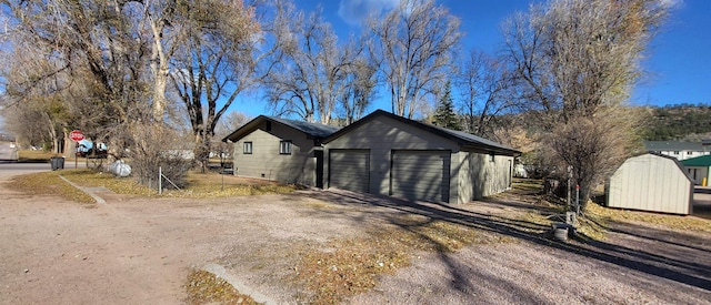 view of property exterior with a garage and a storage unit