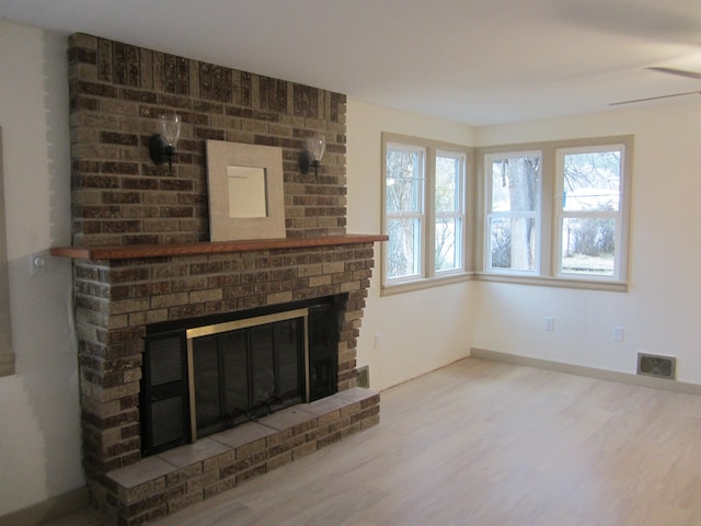 unfurnished living room with hardwood / wood-style flooring and a brick fireplace