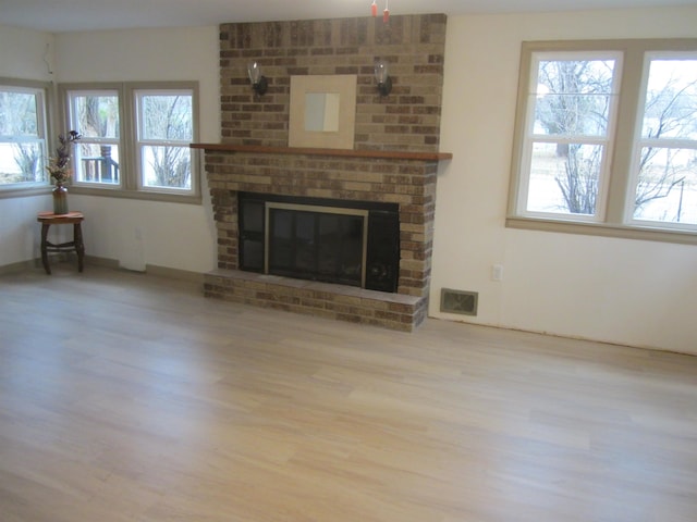 unfurnished living room with light hardwood / wood-style floors and a brick fireplace