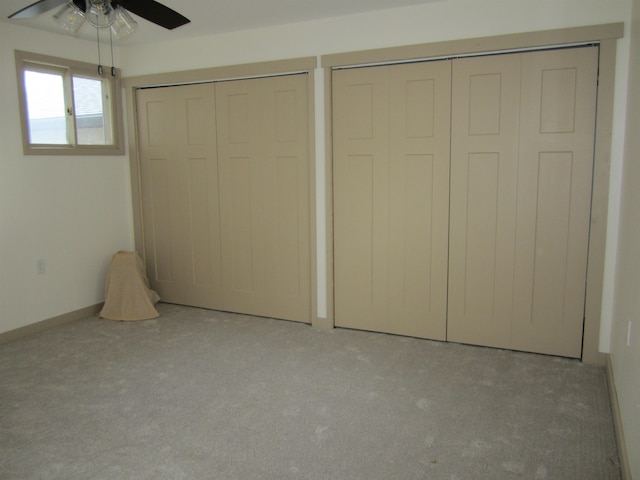 unfurnished bedroom featuring light colored carpet, ceiling fan, and multiple closets